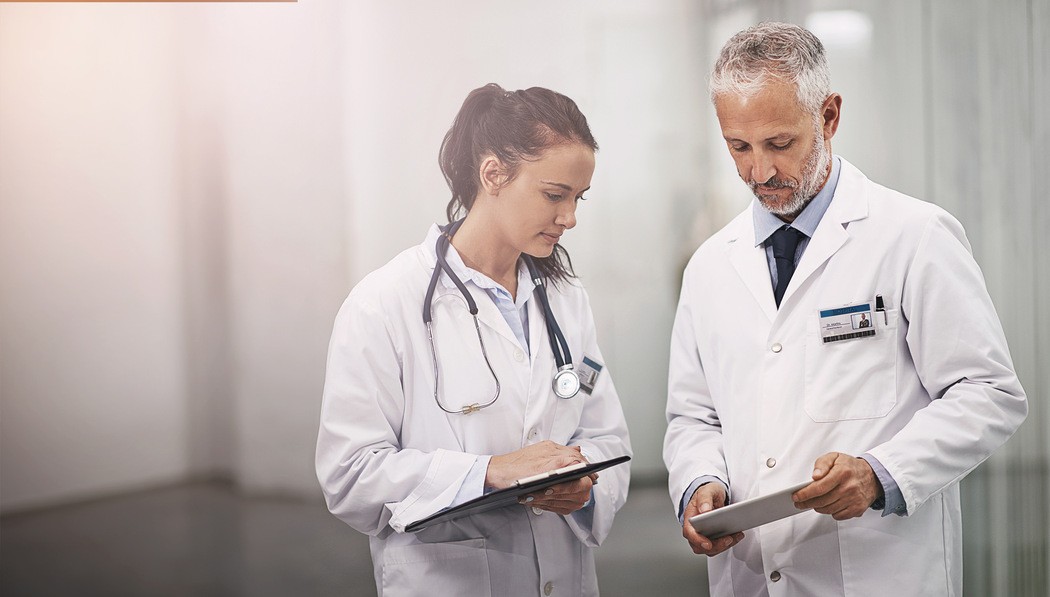 Equipe médica avaliando informações clínicas em tablet para encaminhamento de cirurgia de emergência