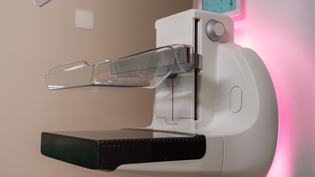  Imagem aproximada de um equipamento de mamografia digital com placas de compressão e iluminação lateral, ilustrando artigo sobre mamografia