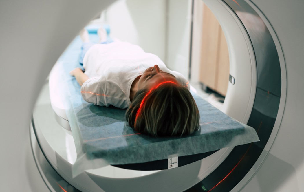 Paciente posicionada corretamente em tomógrafo com laser de centralização, seguindo protocolos de segurança do paciente em exames de imagem