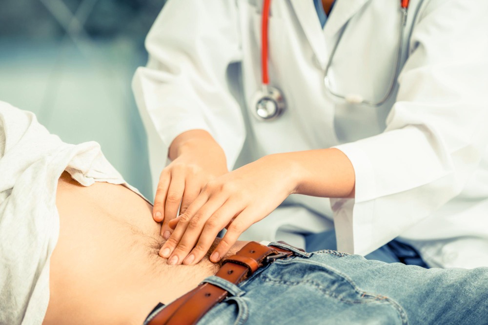 Médica examinando a região abdominal de paciente deitado em ambiente de atendimento, com foco na palpação da barriga durante avaliação clínica, ilustrando artigo sobre apendicite sintomas
