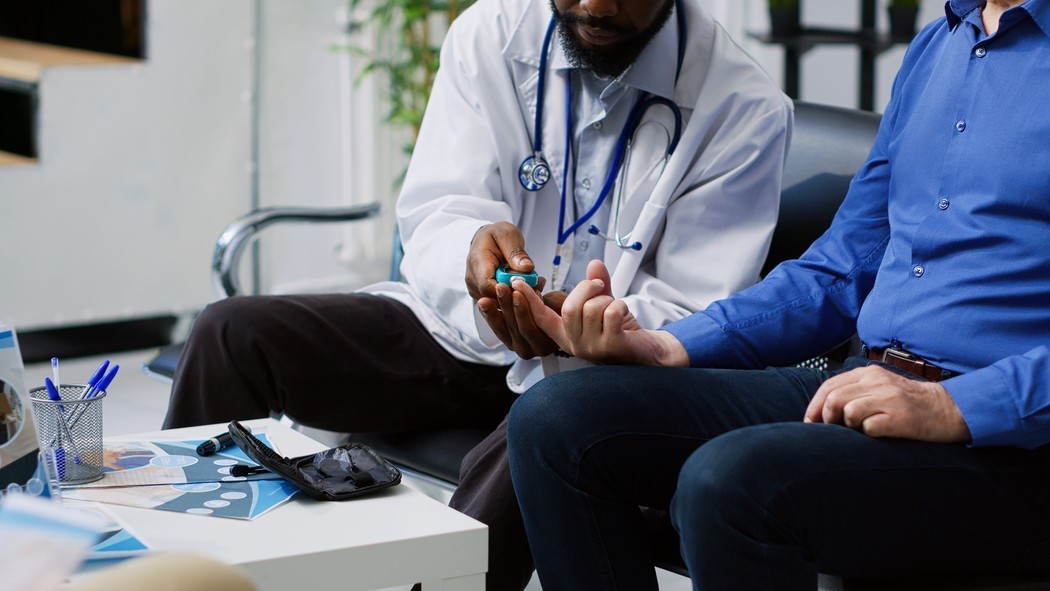 Médico faz exame rápido de sangue no dedo do paciente durante consulta para avaliar possíveis sintomas de diabetes