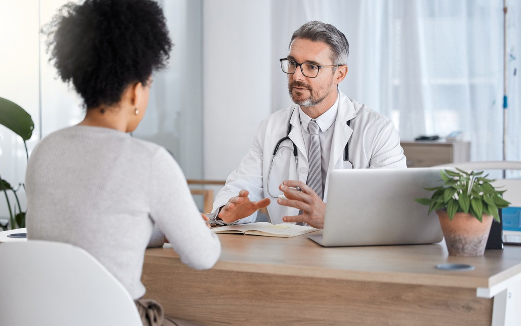  Médico conversando com paciente em consultório sobre sintomas de dor de cabeça forte durante consulta médica 