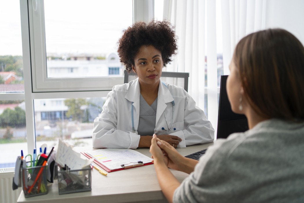 Médica de jaleco com estetoscópio conversando com paciente em consultório, ilustrando orientação sobre nódulo na mama e quando buscar investigação