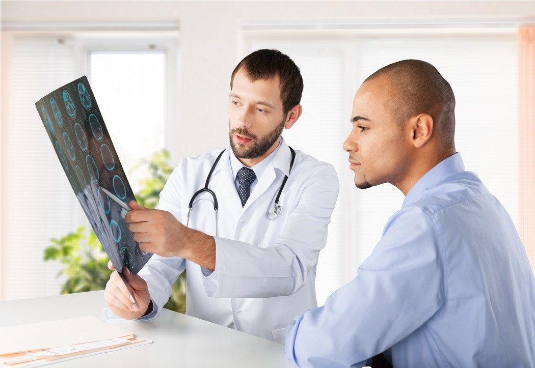 Médico explicando resultado de exame de imagem relacionado ao pet ct oncológico para paciente durante consulta