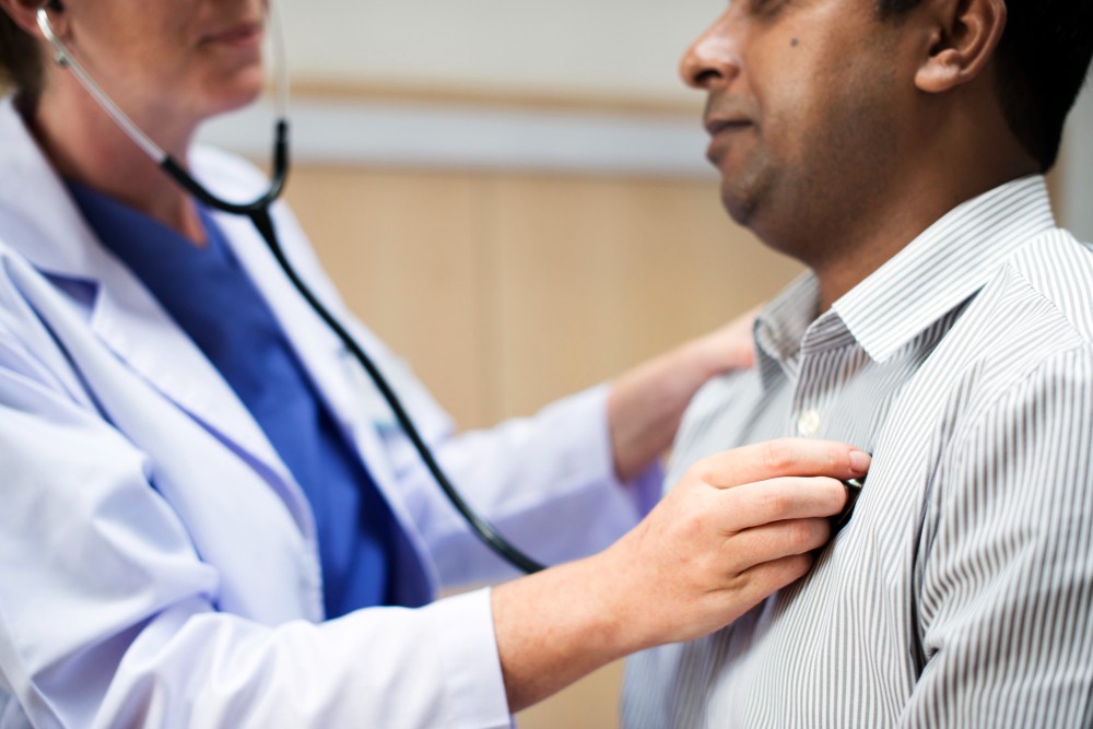 Médico examinando o coração do paciente com estetoscópio para avaliar pressão alta