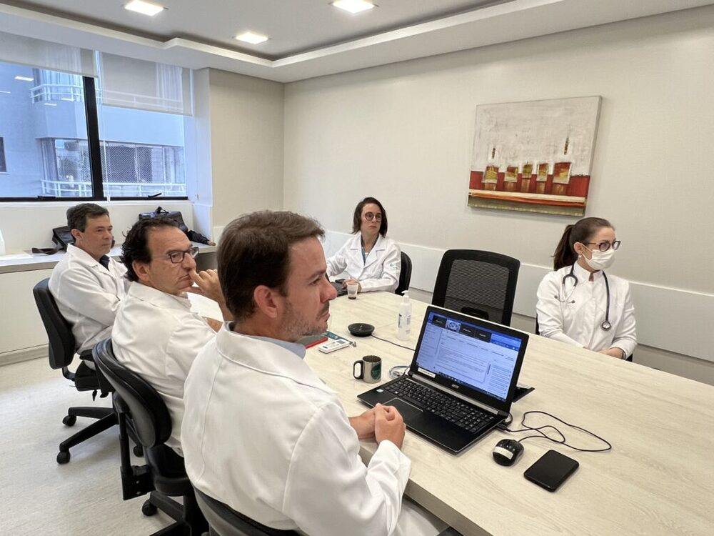Equipe médica reunida em sala de reunião analisando exames em computador, ilustrando artigo sobre tomografia o que é e para que serve.